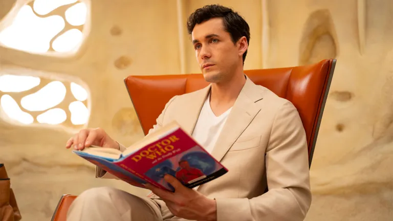 Conrad sentado em uma cadeira, lendo um livro.