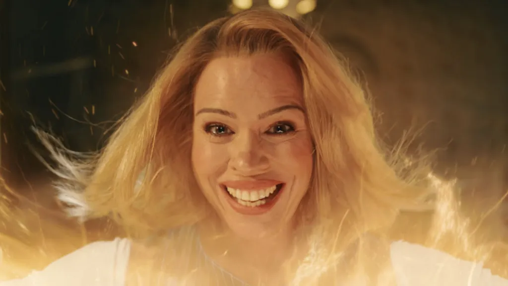 Billie Piper sorrindo, com os olhos cheio de lágrimas, envolta por uma luz amarela, no meio da regeneração.